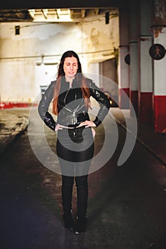 Portrait of young female model dressed in black leather posing casually in an urban setting