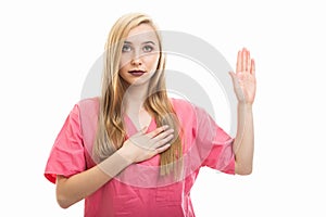 Portrait of young female nurse wearing scrubs taking oath