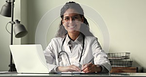 Portrait of young female physician in uniform sit at desk