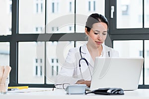 Portrait of young female physician working on laptop in the office