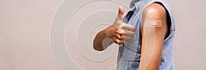 Portrait of a young female  showing thumbs up after getting a vaccine. standing on white background