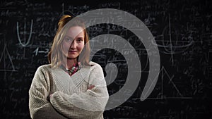 Portrait of young female student stands in front of blackboard with mathematics formulas