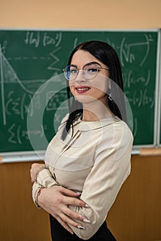 portrait of young female teacher against blackboard with math formula in classroom