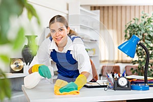 Portrait of a young female worker cleaning an office desk