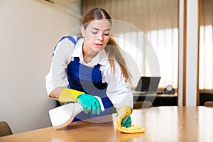 Portrait of a young female worker cleaning an office desk