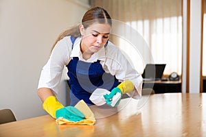 Portrait of a young female worker cleaning an office desk