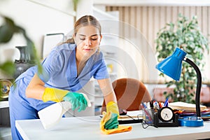 Portrait of a young female worker cleaning an office desk