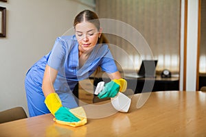 Portrait of a young female worker cleaning an office desk