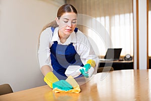 Portrait of a young female worker cleaning an office desk