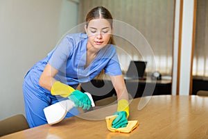 Portrait of a young female worker cleaning an office desk