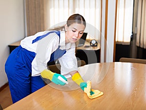 Portrait of a young female worker cleaning an office desk