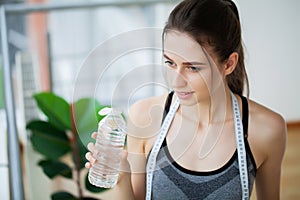 Portrait young fit woman drinking water during traning in the gym.