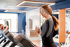 Portrait of young fit woman on modern treadmill in gym