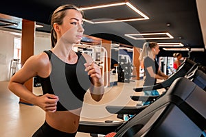 Portrait of young fit woman on modern treadmill in gym