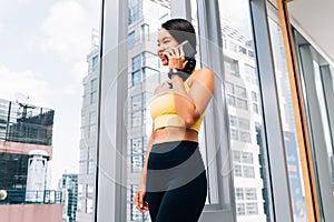 Portrait of young fit woman talking on the hone at high rise gym. Female fitness model image photo