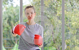 Portrait of young fitness sporty woman in sportswear with red boxing gloves punching hit. Select focus on the glove. healthy