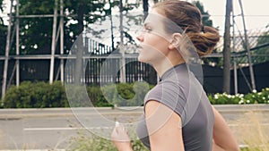 Portrait young fitness woman running at morning jog on summer street