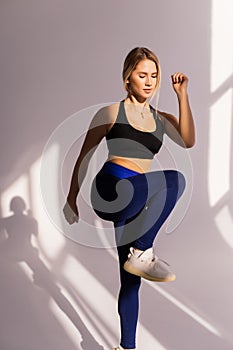 Portrait of young fitness woman in sportswear posing and jumping at gym