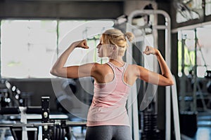 Young fitness woman workout in the gym, female model in sportswear showing her muscles