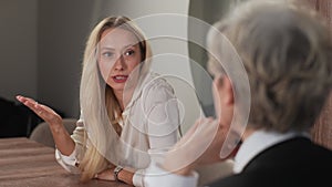 Portrait of young frustrated woman talking to mature female psychologist during consultation session. Disappointed in