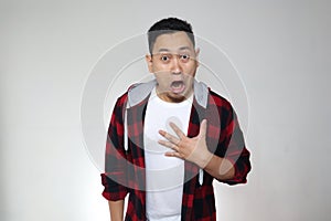 Portrait of young funny Asian man, gesturing shocked or surprised expression with mouth open, over white