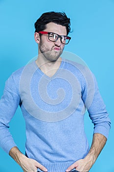 Portrait of Young Funny Caucasian Man in Glasses Grimacing Against Seamless Blue Backgroundr