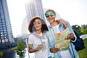 Portrait of young funny couple in sunglasses using navigation map and smartphone looking interested amazed beautiful