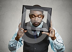 Portrait young funny executive man sticking head in picture frame looking around