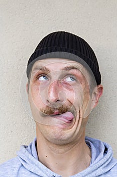 Portrait of young funny man with sticking tongue isolated on gray background.