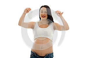 Portrait of young funny pregnant woman with little socks in her hands isolated on white background