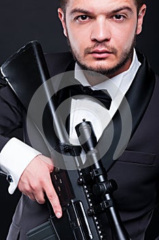 Portrait of young gangster holding armed rifle