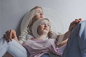 Portrait of young gay couple, girls lesbian sitting and hugging on background white wall. Concept of love, gay marriage and pride