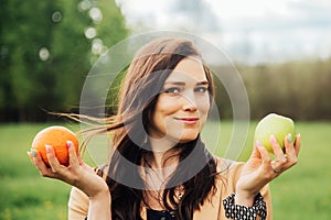 Portrait Of Young Girl. beautiful woman holding green apple and orange deciding what to choose