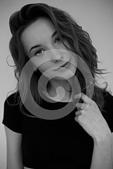 Portrait of a young girl in a black T-shirt looking at the camera . Black and white vertical photo