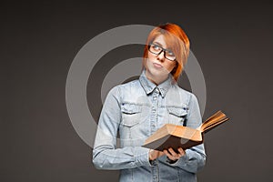 Portrait of young girl with book over grey background. Copy spac