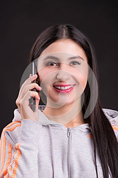 Portrait of a young girl with braces talking on a cell phone on a black background