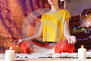 Portrait of a young girl in bright clothes practicing meditation in a crafting room surrounded by candles. Newage