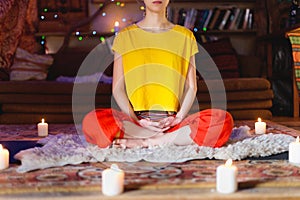 Portrait of a young girl in bright clothes practicing meditation in a crafting room surrounded by candles. Newage