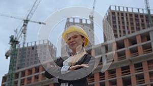 Portrait of a young girl in a business suit and a yellow hard construction hat. female engineer on a construction site