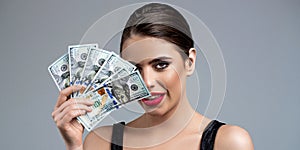 Portrait of a young girl covering her face with money banknotes. Girl holding cash money in dollar banknotes. Woman