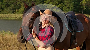 Portrait of young girl in cowboy hat near a horse.