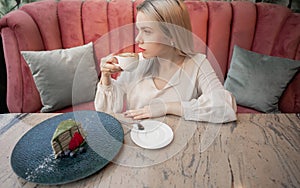 Portrait of young girl drinking coffee and eating dessert