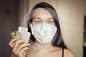 Portrait of young girl with ear loop face mask with pharma drugs - blisters - in hand