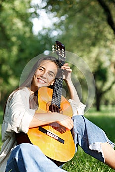 Portrait of a young girl guitarist who smiles and holds a guitar in her hands. Girl-musician, music, hobby