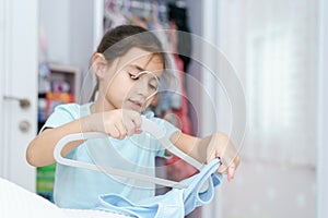 Portrait Young Girl Hanging Clothes On Rack At Home.