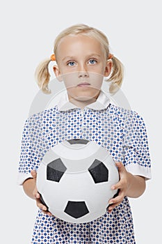 Portrait of a young girl holding soccer ball over white background