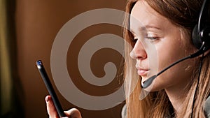 Portrait of a young girl in a hoodie and with a headset. Call center worker