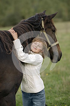 Portrait of a young girl model that hugs the horse's neck with his eyes closed. Lifestyle