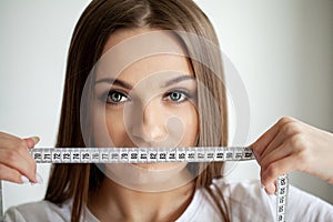 Portrait young girl with open mouth looking at a measuring tape