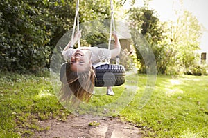 Portrait Of Young Girl Playing On Tire Swing In Garden